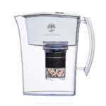 Eine weiße Wasserfilterkanne von Lotus Vita mit einer sichtbaren, mehrschichtigen Filterkartusche aus Aktivkohle und Mineralsteinen.