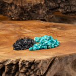 Eine sorgfältig arrangierte Mischung aus leuchtend türkisfarbenen und tiefschwarzen Edelsteinen, präsentiert auf einer rustikalen Holzoberfläche.