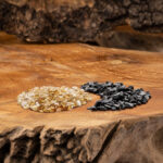 Eine Mischung aus goldgelben Beryll- und schwarzen Turmalin-Edelsteinen, arrangiert auf einer rustikalen Holzoberfläche.