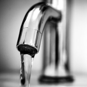 Klares Wasser strömt aus einem modernen Chrom-Wasserhahn, ein Symbol für die Reinheit von gefiltertem Leitungswasser.