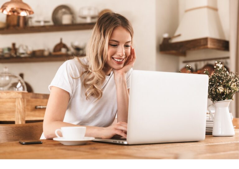 Eine junge Frau sitzt lächelnd an ihrem Laptop und nimmt am Lotus Vita Partnerprogramm teil.